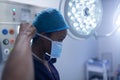 Female surgeon wearing surgical mask in operation theater at hospital Royalty Free Stock Photo