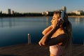 Side view of young sporty blonde woman in workout clothes putting on wireless headphones to start running in city park Royalty Free Stock Photo