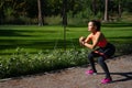 Side view of young sporty woman exercising and doing squats standing on a running way in the urban park . Training outdoor and Royalty Free Stock Photo