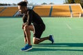 Side view of young strong African American sportsman on workout at city stadium