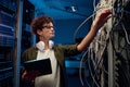 Side view of young teenager boy checking wires connection in server cabinet