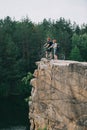 side view of young trial bikers standing on rocky cliff with blurred pine forest Royalty Free Stock Photo