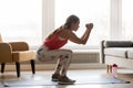 Side full-length view woman wearing activewear makes deep squat