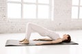 Side view of young woman doing gymnastics the half bridge pose in fitness studio or home, practices yoga warming up Royalty Free Stock Photo