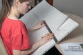 Side view of a young woman with a graphics tablet draws a sketch with a ruler and a pencil Royalty Free Stock Photo