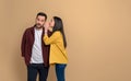 Side view of young woman hiding her mouth while telling secret to her charming boyfriend. Couple sharing gossips with each other Royalty Free Stock Photo