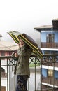 Side view Young woman in khaki jacket with umbrella in rainbow pattern in drops standing on the terrace in the rain Royalty Free Stock Photo