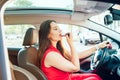 Side view young woman looking in rear view mirror and putting make up in car. Modern busy life. beautiful girl sitting in drivers Royalty Free Stock Photo