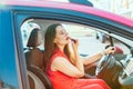 Side view young woman looking in rear view mirror and putting make up in car. Modern busy life. beautiful girl sitting in drivers Royalty Free Stock Photo