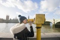 Side view of young woman looking through telescope by river Thames, London, UK Royalty Free Stock Photo