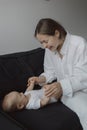 Side view of a young woman playing with her little baby in bed Royalty Free Stock Photo