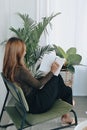 Young woman sitting on comfortable chair and reading book. Royalty Free Stock Photo