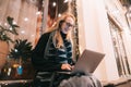 Side view of young woman using laptop on street with night city Royalty Free Stock Photo