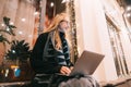 Side view of young woman using laptop on street with night city Royalty Free Stock Photo