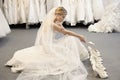 Side view of young woman in wedding dress confused while selecting footwear