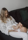 Side view of a young woman playing with her little baby in bed Royalty Free Stock Photo