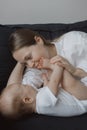 Side view of a young woman playing with her little baby in bed Royalty Free Stock Photo