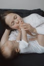 Side view of a young woman playing with her little baby in bed Royalty Free Stock Photo