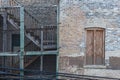 Side of vintage brick building with wooden fire escape staircase protected by chicken wire in Chicago Royalty Free Stock Photo