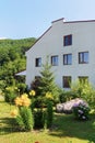 The side wall of the two-story building and the garden behind it with yellow flowers and lawn Royalty Free Stock Photo