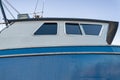 Side windows in the cabin of a docked blue fishing vessel Royalty Free Stock Photo