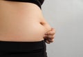 Side of woman hand catching fat body belly paunch , diabetic risk factor . Royalty Free Stock Photo