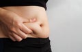 Side of woman hand catching fat body belly paunch , diabetic risk factor . Royalty Free Stock Photo