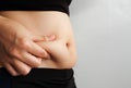 Side of woman hand catching fat body belly paunch , diabetic risk factor . Royalty Free Stock Photo