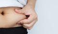 Side of woman hand catching fat body belly paunch , diabetic risk factor . Royalty Free Stock Photo