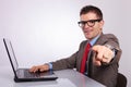 Side of young business man at laptop, pointing at you Royalty Free Stock Photo