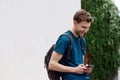 Side of young man with backpack looking at mobile phone and smiling Royalty Free Stock Photo