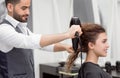 Sideview of Arabian hairstyler drying smiling female client`s curly hair.