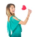 Sideview of beautiful woman holding red heart-shaped lollypop in front of her body Royalty Free Stock Photo