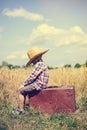 Sideview of little boy sitting on old suitcase in