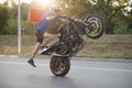 Sideview of moving biker riding on one wheel.