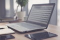 Sideview of office desktop with blank laptop and various tools. Royalty Free Stock Photo