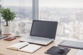 Sideview of office desktop with blank laptop and various tools. Royalty Free Stock Photo