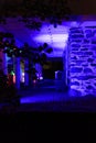 Sideview of an old-fashioned eerie looking brick & mortar building`s porch at night, illuminated in blue