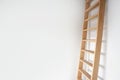 Sideview of a wooden ladder leaning against white wall modern design, stylish stairs in bright room with copy space