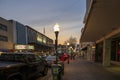 A sidewalk along Broughton Street lined with restaurants, shops, black light posts, bare trees and people standing with cars Royalty Free Stock Photo