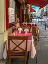 Sidewalk cafe tables set with red and rose cloths and carefully folded napkins