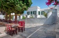 Sidewalk cafe with tables under the shadow of the trees in Pirgos village, Tinos Island, Cyclades, Greece Royalty Free Stock Photo