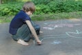 Sidewalk chalk drawings of barefoot teenage boy wearing blue t-shirt and jeans