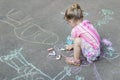 Sidewalk chalk drawings of little Caucasian girl wearing pink ruffle skirt