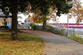 A sidewalk covered with fallen autumn leaves with red brick and cobble stone surrounded by gorgeous green and autumn colored trees Royalty Free Stock Photo