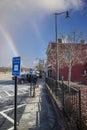 A sidewalk in front of O`neal Plaza with a black fence, bare winter trees, shops, restaurants with cars parked