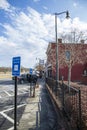 A sidewalk in front of O`neal Plaza with a black metal fence, bare winter trees, shops and restaurant with cars parked