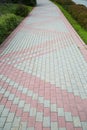 The sidewalk is made of rectangular pavers of gray pink color.