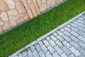 Sidewalk paved with cement bricks and lawn with green grass
