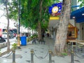 A sidewalk for pedestrians with a few trees, shophouses that are closed and the door gets vandalism and the main road beside it Royalty Free Stock Photo